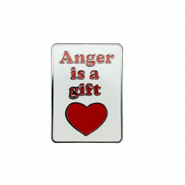 A pin with a rectangular silver-colored badge and a red heart, with the text 'Anger is a gift' on it.