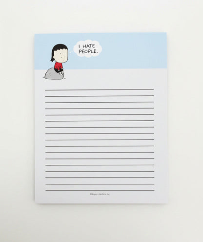 A lined notepad featuring a light blue header with a cartoon girl sitting on a rock and a speech bubble that reads 'I HATE PEOPLE.' The notepad is photographed against a plain light gray wall.