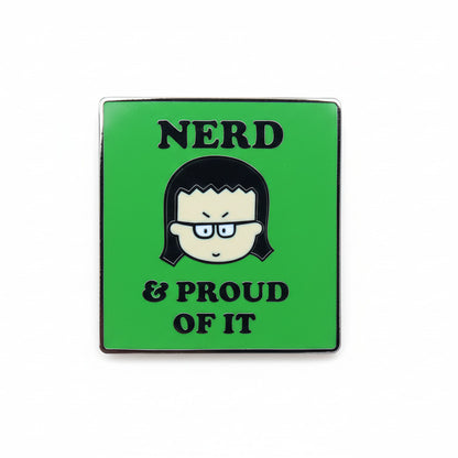 A pin badge with a green background featuring text and Kim, the Angry Little Asian Girl, a cartoon depiction of a character wearing glasses. The text reads 'NERD & PROUD OF IT'.