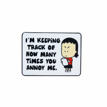 A pin with an illustration and text on it, depicting Kim, the Angry Little Asian Girl, a character and saying 'I'M KEEPING TRACK OF HOW MANY TIMES YOU ANNOY ME.'.
